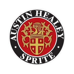 Può includere: Emblema circolare con la scritta "AUSTIN HEALEY SPRITE" in bianco su un bordo nero. Il centro dell'emblema presenta uno sfondo rosso con uno stemma dorato e un design dettagliato.
