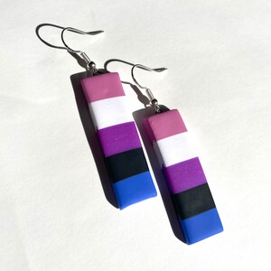 May include: A pair of dangle earrings with a silver hook and a rectangular charm. The charm is made of polymer clay and features five horizontal stripes in the colours of the genderqueer flag: pink, white, purple, black, and blue.