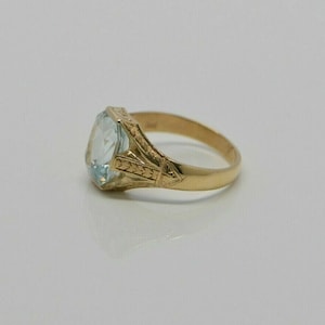 May include: A gold ring with a light blue gemstone set in a filigree design.