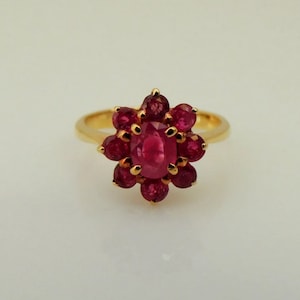 May include: A gold ring with a cluster of red rubies set in a flower shape.
