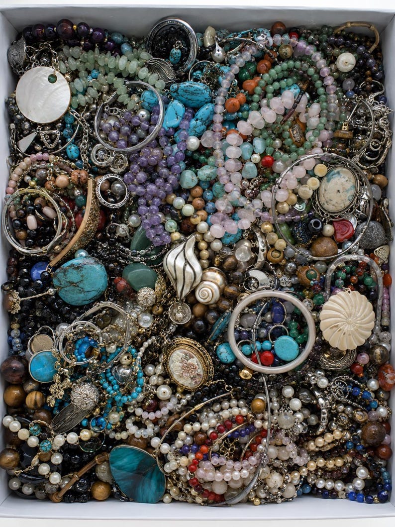 May include: A large collection of assorted jewellery pieces packed into a rectangular box, including various beaded necklaces, metal chains, turquoise stones, pearl strands, shell pendants, and intricate brooches in a mix of colours and textures.