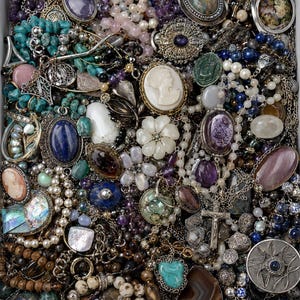 May include: A collection of assorted jewellery pieces including necklaces, bracelets, and brooches featuring various gemstones like turquoise, amethyst, and lapis lazuli, alongside pearls, cameos, and a silver crucifix pendant in a white tray.