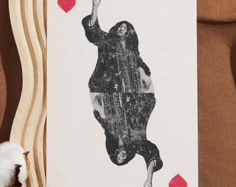 May include: A black and white photograph of a person in a long coat with their arms raised, holding a red heart in each hand. The photo is on a white background.