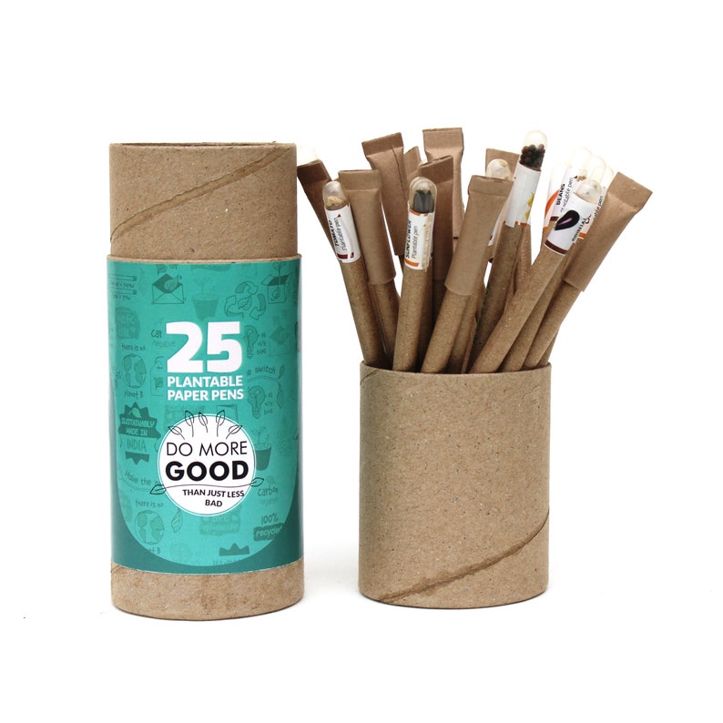 Pode incluir: Um conjunto de 25 canetas de papel plant&aacute;veis em um tubo de papel&atilde;o marrom. O tubo tem um r&oacute;tulo verde e branco com o texto "25 canetas de papel plant&aacute;veis" e "Fa&ccedil;a mais bem do que simplesmente menos mal".