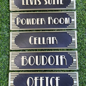 Puede incluir: Cinco letreros decorativos negros y dorados con diferentes nombres de habitaciones. Los letreros dicen "Elvis Suite", "Powder Room", "Cellar", "Boudoir" y "Office".