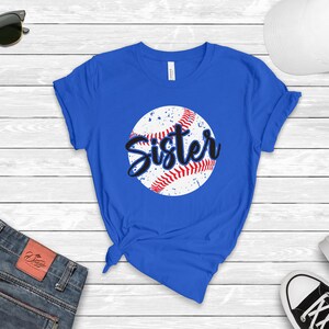 May include: A royal blue t-shirt with a white baseball graphic and the word "Sister" in black text.