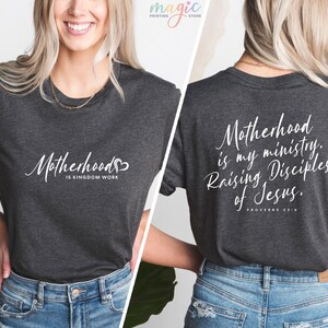 K&ouml;nnte beinhalten: Ein dunkelgraues T-Shirt mit wei&szlig;em Text, der auf der Vorderseite "Motherhood is Kingdom Work" und auf der R&uuml;ckseite "Motherhood is my ministry. Raising Disciples of Jesus. Proverbs 22:6" lautet.