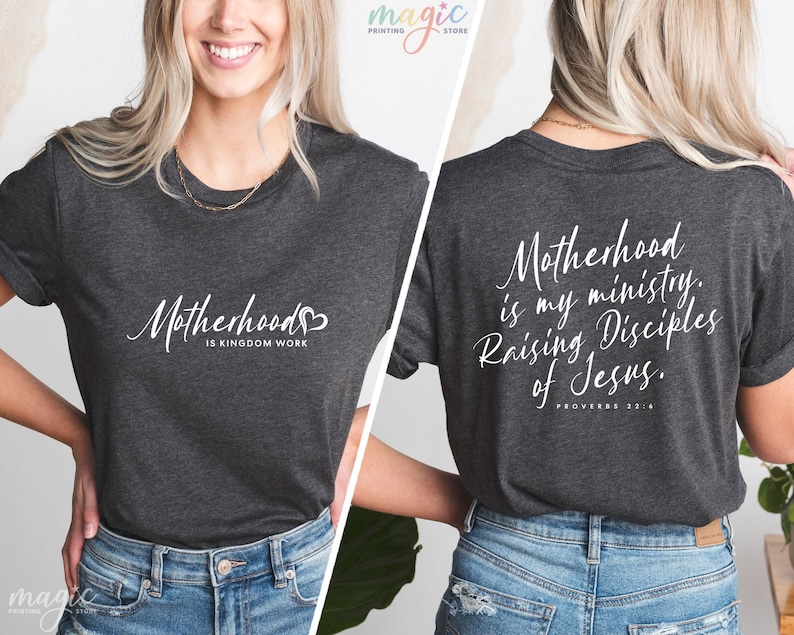 K&ouml;nnte beinhalten: Ein dunkelgraues T-Shirt mit einem wei&szlig;en Aufdruck, der auf der Vorderseite "Motherhood is Kingdom Work" und auf der R&uuml;ckseite "Motherhood is my ministry. Raising Disciples of Jesus. Proverbs 22:6" lautet.