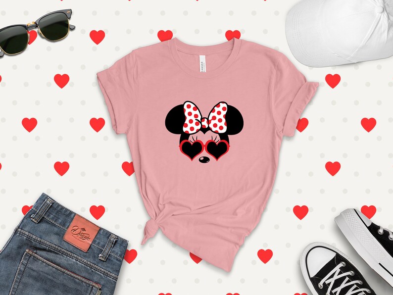 May include: Pink t-shirt with a black and white Minnie Mouse graphic wearing red heart-shaped sunglasses and a red and white polka dot bow.