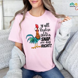 May include: Pink t-shirt with a cartoon rooster and the text "y'all realize I'm gonna snap one day right?"
