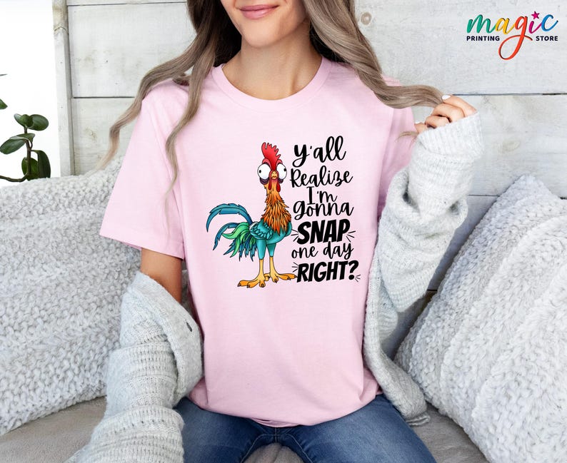 May include: Pink t-shirt with a cartoon rooster and the text "y'all realize I'm gonna snap one day right?"