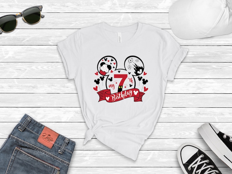 以下が含まれることがあります： 白地に赤と黒のミッキーマウスのデザインが施されたTシャツ。デザインには、数字の7、