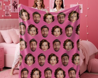Può includere: Una coperta rettangolare in pile con un motivo ripetuto di due volti distinti stampati su uno sfondo rosa a tinta unita. Il design è composto da file alternate di una persona con capelli castani corti e una persona con la barba.
