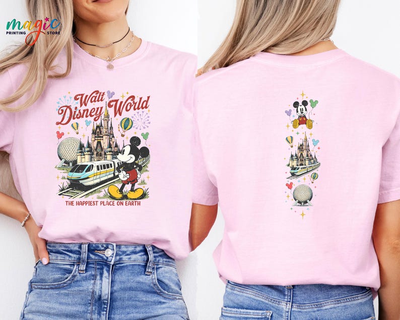 May include: Pale pink t-shirt with a vibrant Walt Disney World graphic. The design includes Mickey Mouse, a monorail, and a castle, with the text "Walt Disney World" and "The Happiest Place on Earth." The back of the shirt has a smaller version of the design.
