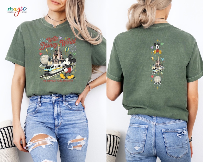 May include: Green t-shirt with a colourful graphic of Mickey Mouse, a train, and a castle with the text "Walt Disney World". The back of the shirt has a vertical design with Mickey Mouse, a castle, and a sphere. The shirt is made of a soft material.