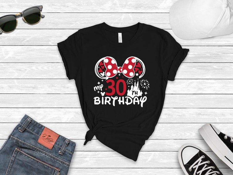 May include: Black t-shirt with a white graphic of Minnie Mouse ears with a red bow and white polka dots. The graphic also includes the text "my 30 birthday" with a white castle and fireworks.