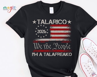 Può includere: Una t-shirt nera a maniche corte con la grafica di una bandiera americana invecchiata e il testo TALARICO, 2026, We the People e I'M A TALAFREAKO stampato in inchiostro bianco e rosso al centro del petto.