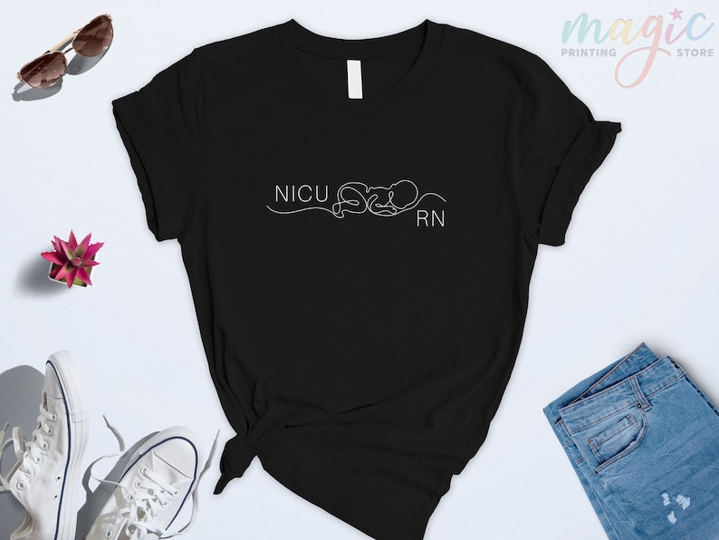 May include: Black t-shirt with a white graphic design that says "NICU RN" with a stylized line drawing of a baby.
