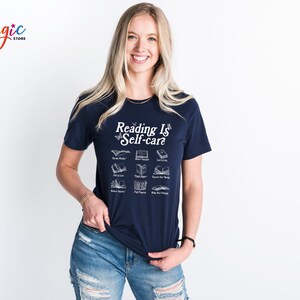 May include: A navy blue t-shirt with a white graphic that says "Reading is Self-care" and features a variety of book illustrations.