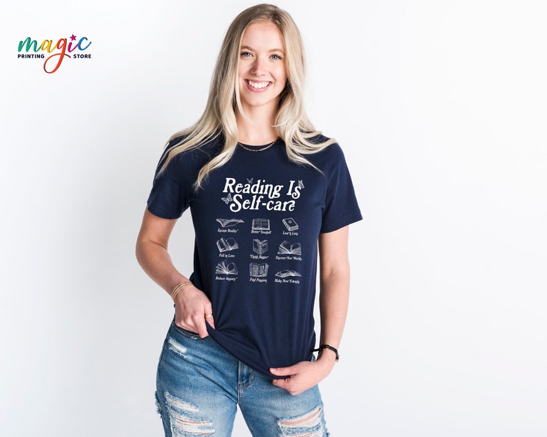 May include: A navy blue t-shirt with a white graphic that says "Reading is Self-care" and features a variety of book illustrations.