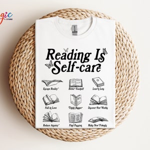 May include: White t-shirt with black text that reads "Reading Is Self-care" and illustrations of open books with text describing the benefits of reading, such as "Escape Reality", "Better Yourself", "Learn Lots", "Fall in Love", "Think Bigger", "Discover New Worlds", "Reduce Anxiety", "Find Passion", and "Make New Friends".
