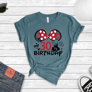 May include: Teal blue t-shirt with a black and red Minnie Mouse ears design. The ears have white polka dots. The text "my 30th birthday" is printed below the ears.