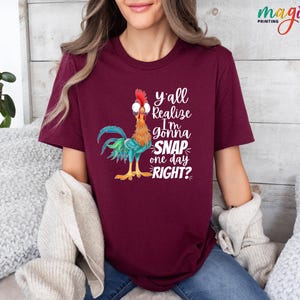 May include: A maroon t-shirt with a cartoon rooster wearing glasses and the text "y'all realize I'm gonna snap one day right?"