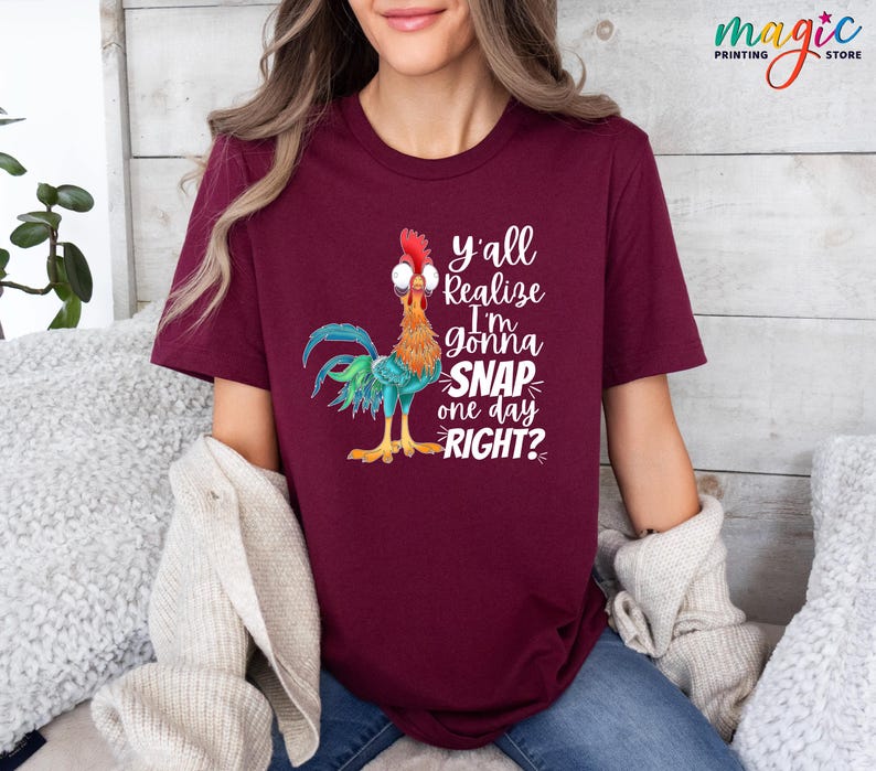 May include: A maroon t-shirt with a cartoon rooster wearing glasses and the text "y'all realize I'm gonna snap one day right?"