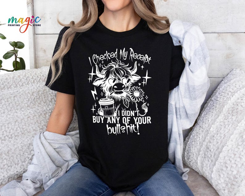 May include: Black t-shirt with a white graphic of a Highland cow, coffee cup, and text that reads "I checked my receipt, I didn't buy any of your bullshit!" The shirt has a crew neck and short sleeves.