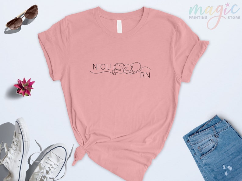 May include: A pink t-shirt with the text "NICU RN" and a line drawing of a baby in a swaddle.