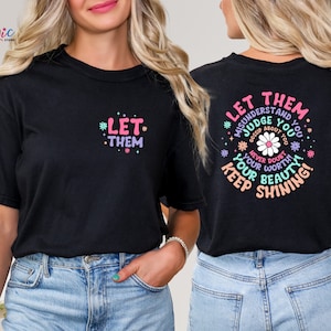 May include: Two black t-shirts with a graphic print of flowers and text. The front shirt says "Let Them" and the back shirt says "Let Them Misunderstand and Judge You Gossip About You Never Doubt Your Worth Keep Shining Your Beauty!"