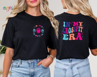 May include: Black t-shirt with a colorful graphic that says "In My CrossFit Era" on the back and a smaller graphic of a kettlebell and barbell with the same text on the front.