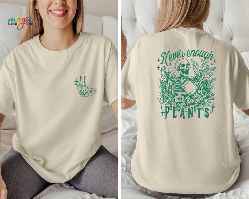 May include: A beige t-shirt with a green skeleton holding a watering can and surrounded by plants. The text "Never enough plants" is printed on the back of the shirt. A small green hand with flowers is printed on the front of the shirt.