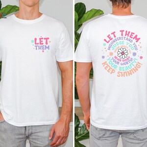 May include: White t-shirt with the text "Let Them" on the front and "Let Them Misunderstand You, Judge You, Gossip About You, Never Doubt Your Worth, Keep Your Beauty Shining!" on the back. The text is surrounded by a circle of flowers.