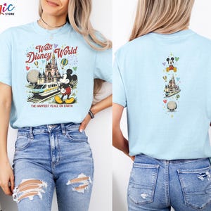 May include: Pale blue t-shirt with a vibrant graphic of Walt Disney World, including Mickey Mouse, a monorail, and Cinderella's castle. The front of the tee reads "Walt Disney World" and "The Happiest Place on Earth."