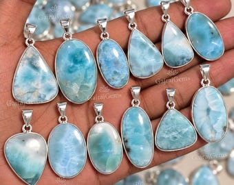 Könnte beinhalten: Eine Sammlung von polierten Larimar-Anhängern in Silberfassung, die verschiedene Formen wie Tropfen und Ovale aufweisen. Jeder Stein zeigt einzigartige hellblaue und weiße Marmorierungen mit einer glatten, glänzenden Oberfläche und einer Silberöse.