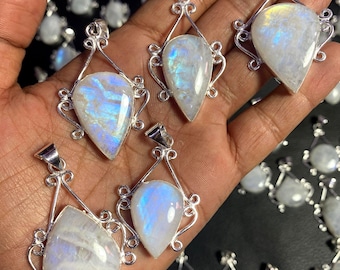 May include: A collection of silver pendants with iridescent moonstone gemstones. The pendants are teardrop shaped and have a delicate, ornate design.
