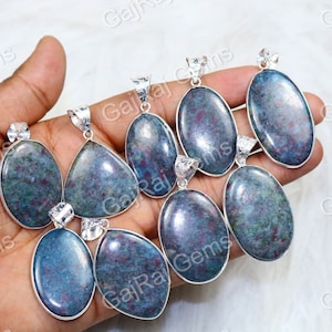 May include: A collection of eight silver pendants with green and red gemstone inserts. The pendants are oval and teardrop shaped.