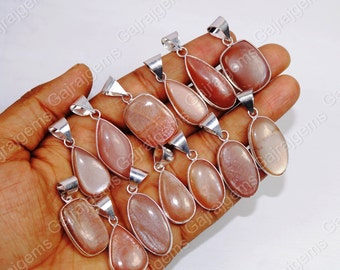 Puede incluir: Una colección de nueve colgantes de plata con piedras preciosas de piedra de sol. Los colgantes son de varias formas, incluyendo ovalada, de lágrima y rectangular. La piedra de sol es de color naranja claro con un efecto brillante.