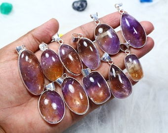 May include: A collection of ten amethyst and citrine gemstone pendants with silver bail settings. The pendants are oval and teardrop shaped and have a gradient of purple and yellow.