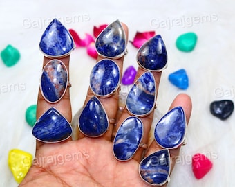 May include: A collection of ten silver rings with blue and white gemstone settings. The rings are arranged on a hand, with the gemstones facing the viewer. The gemstones are all different shapes and sizes, but they are all a similar shade of blue.