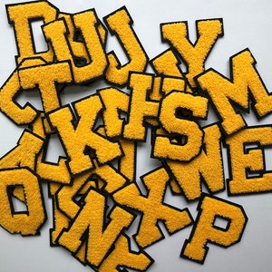 May include: A collection of yellow felt letter patches with black outlines. The letters include D, U, J, Y, T, K, H, S, M, O, N, X, and P.