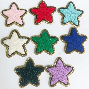May include: Eight embroidered felt star patches with gold glitter trim. The stars are in various colours including pink, red, blue, green, white, black, and purple.