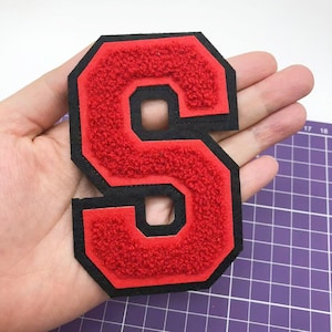 Peut inclure: Lettre S en feutre rouge avec un contour noir. La lettre est épaisse et a une texture légèrement en relief. La lettre mesure environ 7,5 cm de haut.