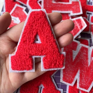 May include: Red felt letter A with white outline. The letter is thick and fuzzy.