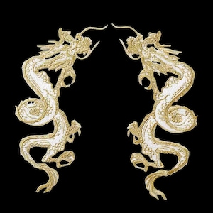 Może przedstawiać: Dwa białe haftowane smoki zwrócone do siebie z złotymi akcentami na czarnym tle.