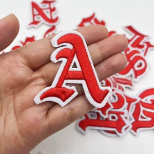 May include: Red embroidered iron-on patches in the shape of the letter A in a gothic font style.