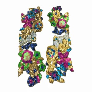 May include: Two gold, green, blue, pink, and silver sequined floral appliques. The appliques are ideal for adding a touch of sparkle to clothing, bags, or home decor projects.