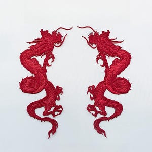 Może przedstawiać: Dwa czerwone haftowane łaty z motywem smoka, zwrócone do siebie, z misternymi detalami i tradycyjnym chińskim wzorem.