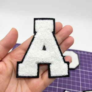 Puede incluir: Letra A de fieltro blanco con contorno negro. La letra mide aproximadamente 10 cm de alto y es perfecta para añadir un toque personalizado a manualidades, ropa o bolsos.